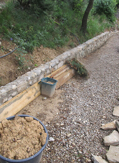 Construction d'un mur de soutènement en pierre sur un terrain en pente.